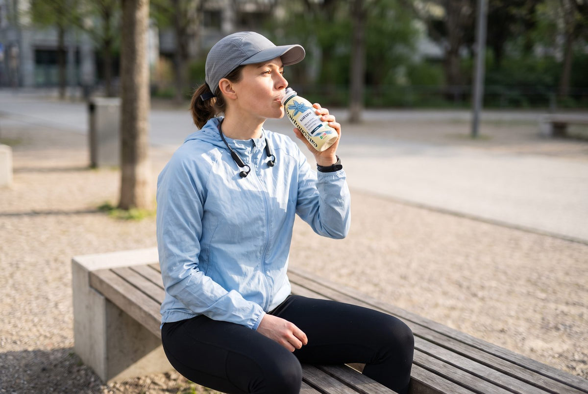 Runner drinking a Saturo drinkable meal on a park bench after a run