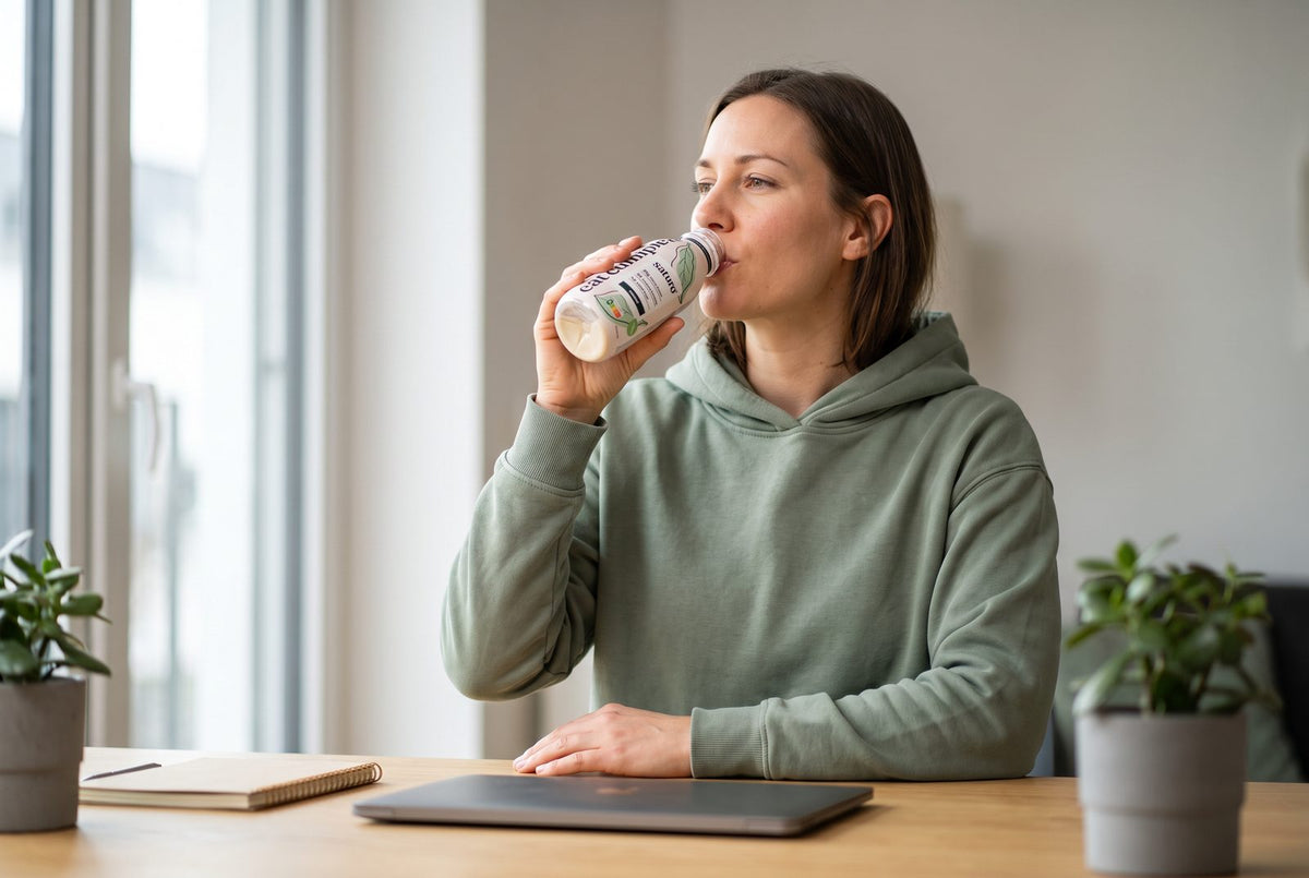 Woman drinking a Saturo Drinkable Meal Natural at her desk during her lunch break