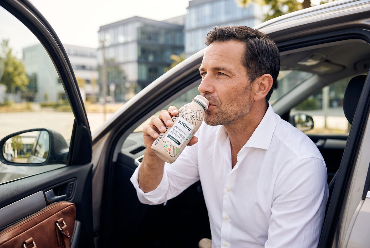 Mann trinkt in der Mittagspause im Auto eine Saturo Trinkmahlzeit