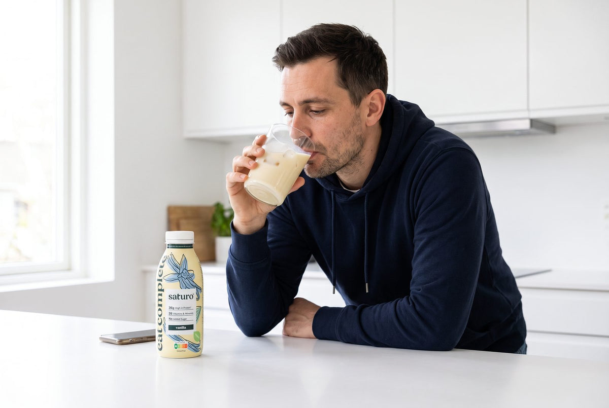 Mann mit Halsschmerzen gießt in der Küche eine kalte Trinkmahlzeit in ein Glas mit Eis