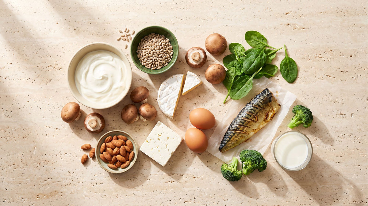 Vitamin-B2-Quellen auf Travertin: Mandeln, Champignons, Spinat, Brokkoli, Joghurt, Käse, Eier und Makrele
